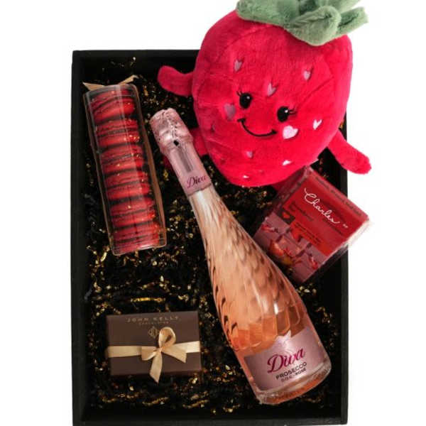 Gift box with strawberry plush, pink sparkling wine, macarons, and chocolates