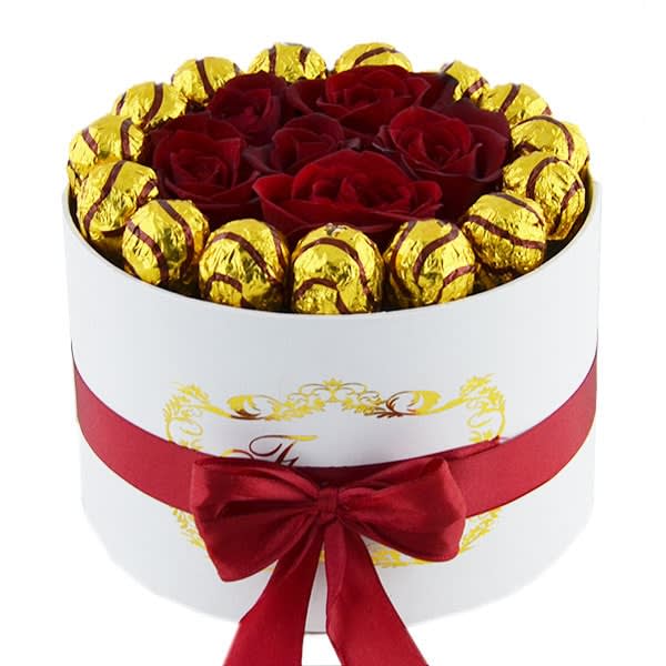 Red roses and gold-wrapped chocolates in a white round box with a red ribbon