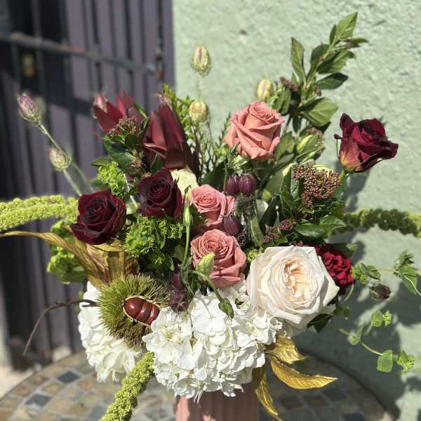 Tall bouquet of roses and white hydrangeas in a pink vase