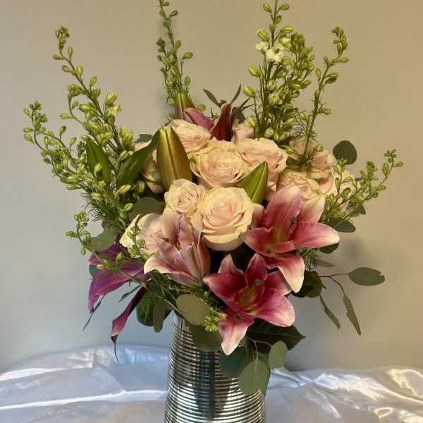 Pink lilies and pale roses arranged in a striped metal vase