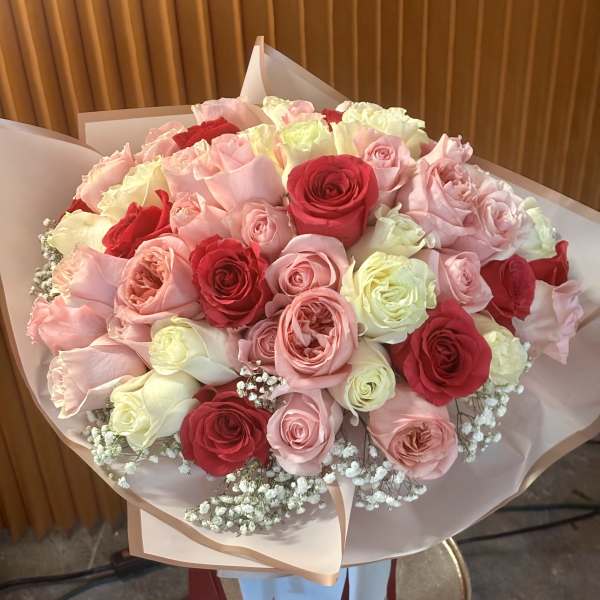 Bouquet of pink, red, and white roses wrapped in pale paper