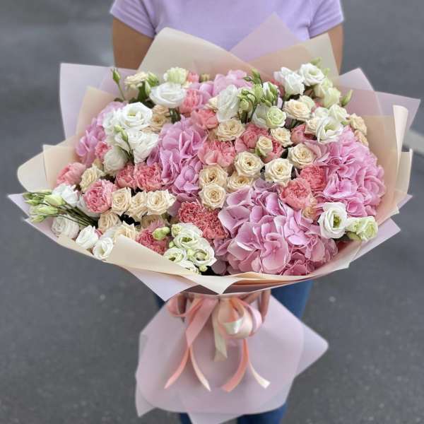 Large bouquet of pink and white flowers wrapped in pastel paper