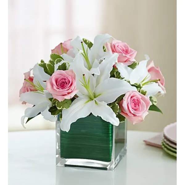 Pink roses and white lilies in a clear square vase