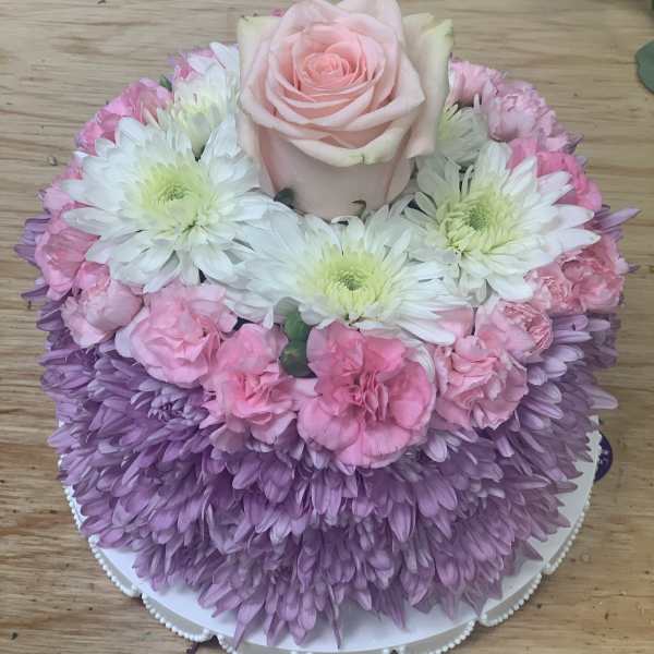 Pink rose and chrysanthemum arrangement on a round white base