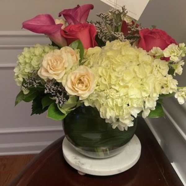 Pink roses and pale hydrangeas arranged in a glass vase