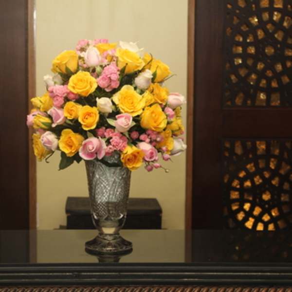Yellow and pink roses arranged in a clear glass vase