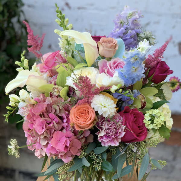 Colorful bouquet with roses, calla lilies, and hydrangeas in a glass vase
