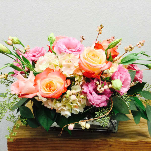 Pink and peach rose arrangement in a low rectangular vase
