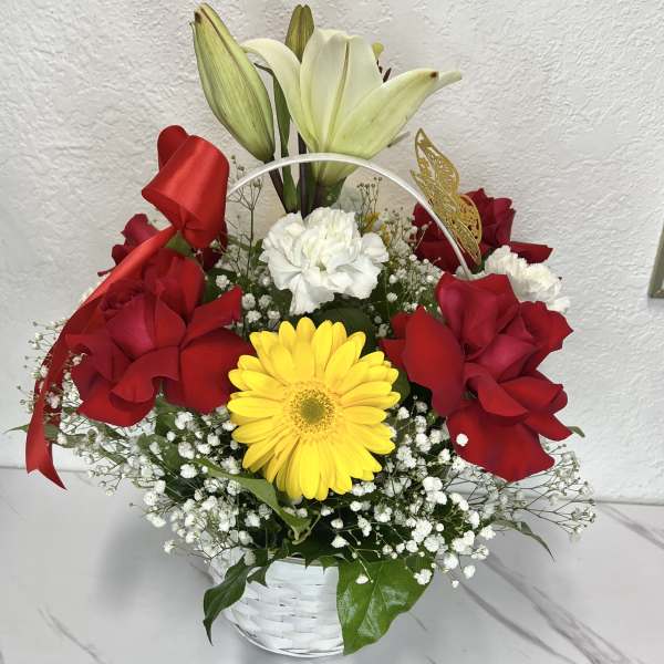 Basket arrangement with red roses, a yellow gerbera daisy, and white lilies