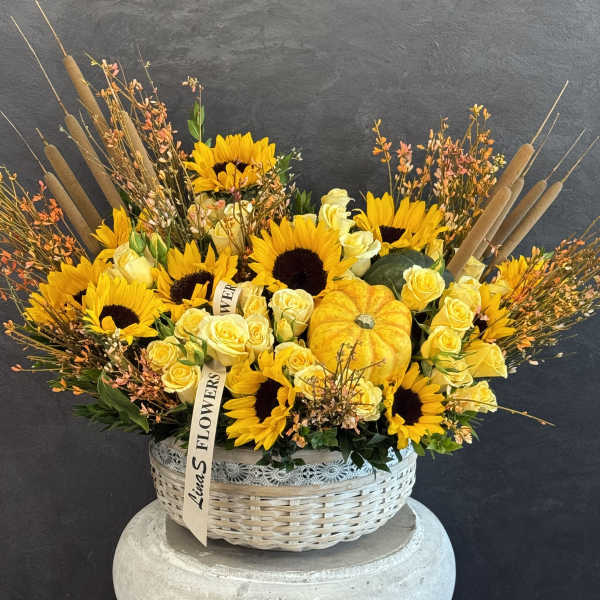 Basket arrangement with sunflowers, yellow roses, and a pumpkin