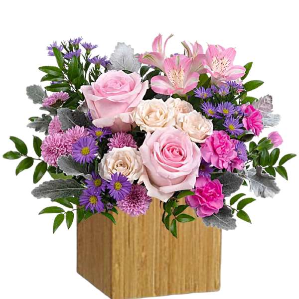 Pink and purple flower arrangement in a wooden cube vase
