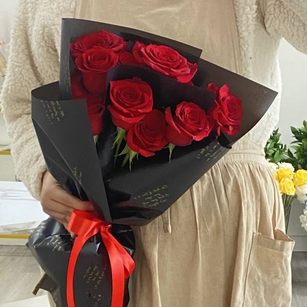 Bouquet of red roses wrapped in black paper with a red ribbon