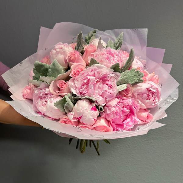 Pink bouquet of roses and peonies wrapped in pale paper