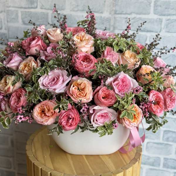 Pink and peach roses arranged in a white bowl vase