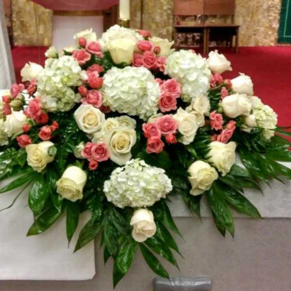 Large white and pink rose arrangement with hydrangeas on a table