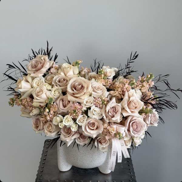 Blush roses and small pink flowers arranged in a white vase