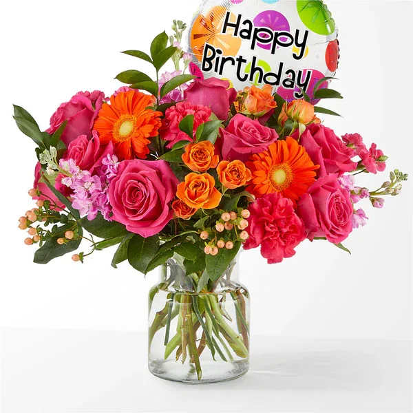 Pink and orange bouquet in a glass vase with a birthday balloon