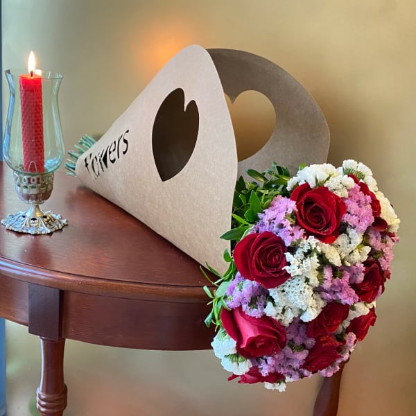 Red rose bouquet beside a lit candle in a glass holder