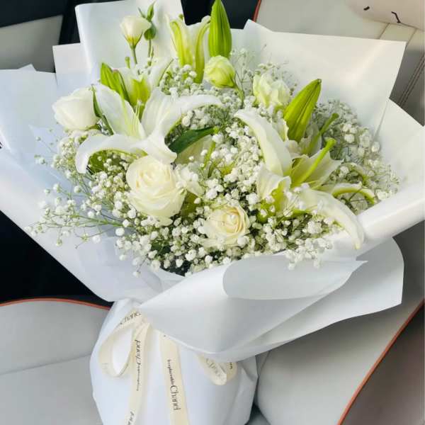 White lilies and roses in a wrapped bouquet