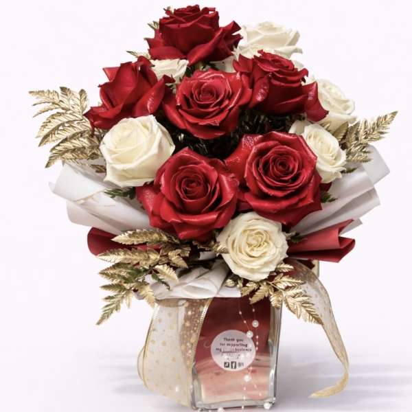 Bouquet of red and white roses in a clear glass vase with gold accents
