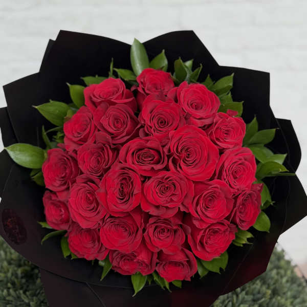 Round bouquet of red roses wrapped in black paper