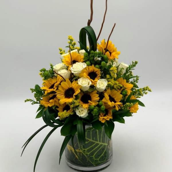 Sunflower and white rose arrangement in a glass vase