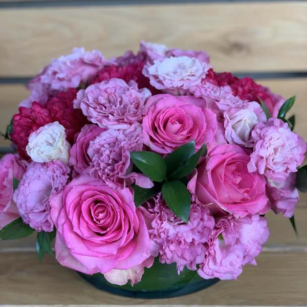 Pink roses and carnations arranged in a low glass bowl