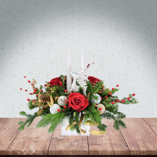 Holiday centerpiece with red roses, candles, and evergreen accents