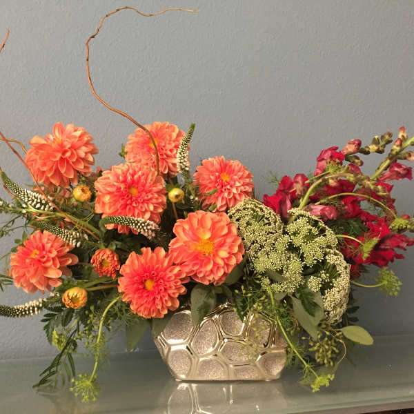 Orange dahlias and red flowers in a metallic vase