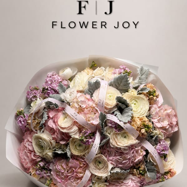 Large pastel bouquet of pink, cream, and lavender flowers wrapped in white paper