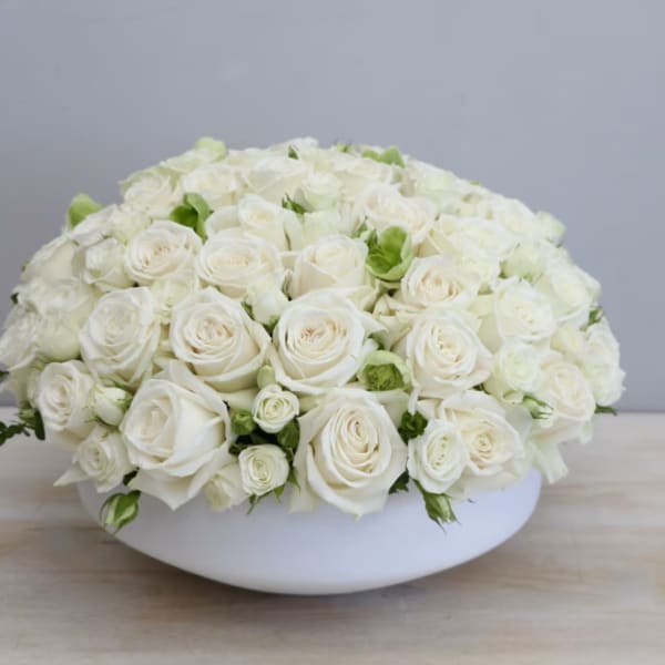 White rose arrangement in a low white bowl