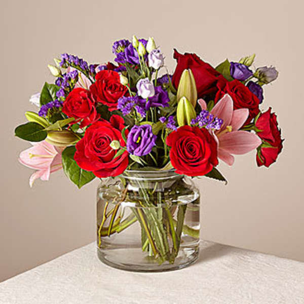 Bouquet of red roses and pink lilies in a clear glass vase