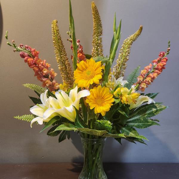 Mixed bouquet with yellow gerbera daisies and white lilies in a glass vase