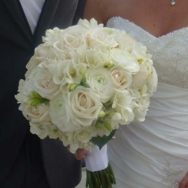 Bride holding a white bouquet of roses and ranunculus