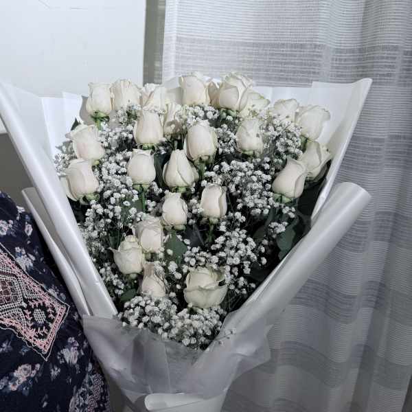 Bouquet of white roses and baby's breath wrapped in white paper