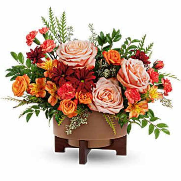 Arrangement of peach roses and orange-red flowers in a low wooden container