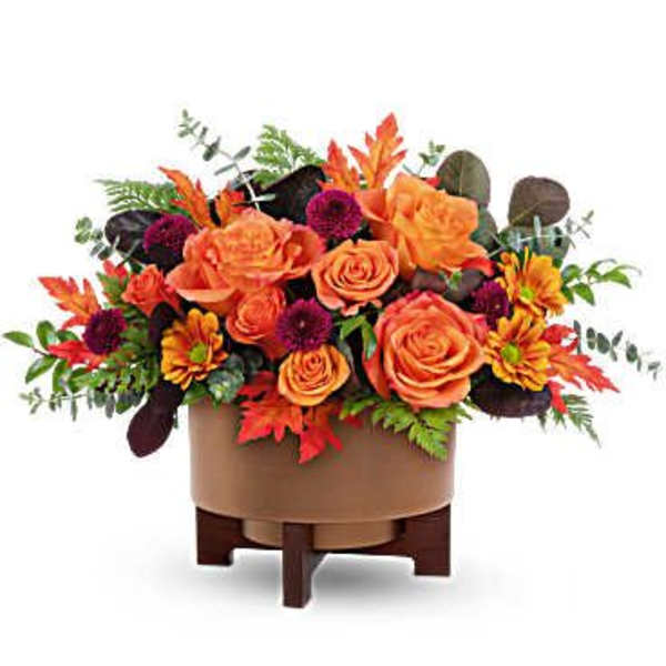 Orange roses and autumn flowers in a round container