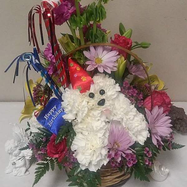 Basket arrangement with a white plush dog and colorful flowers