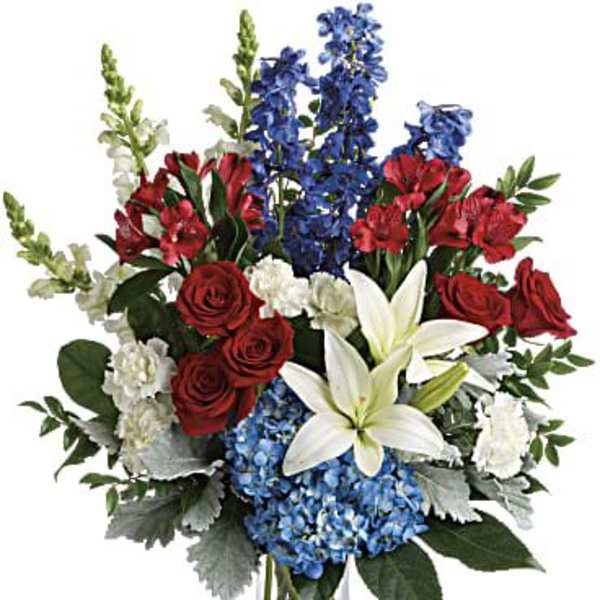 Bouquet of red roses, white lilies, blue flowers, and white snapdragons in a glass vase