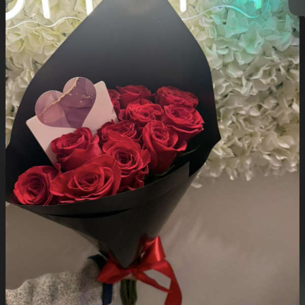 Bouquet of red roses wrapped in black paper with a red ribbon