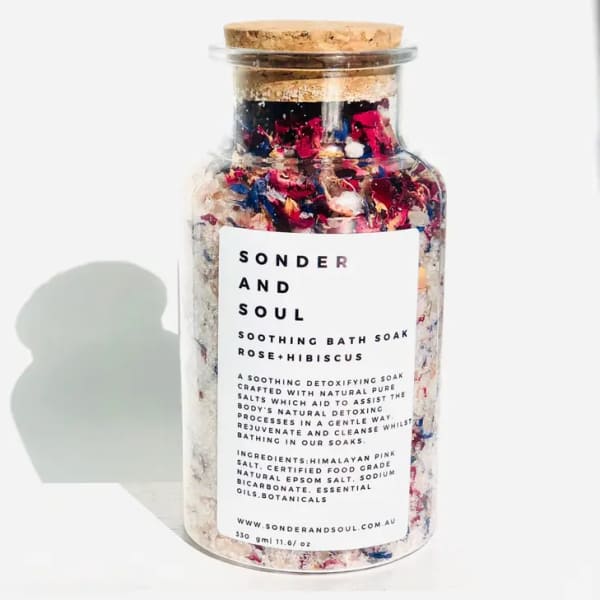 Glass jar of rose and hibiscus bath soak with a cork lid