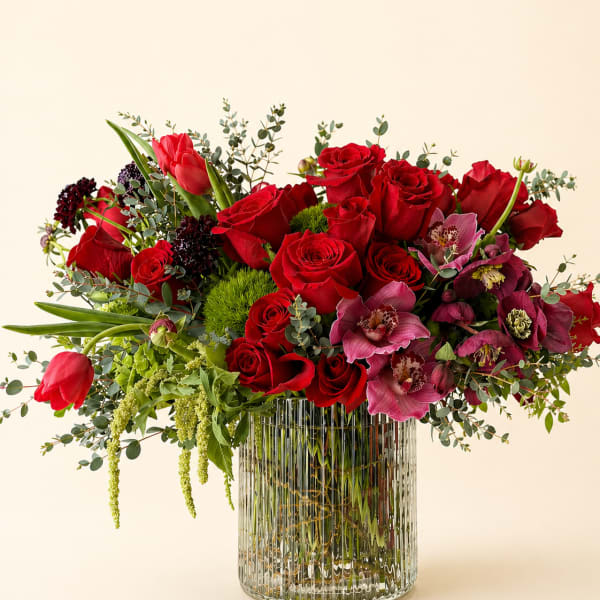 Red roses and pink orchids in a clear ribbed glass vase
