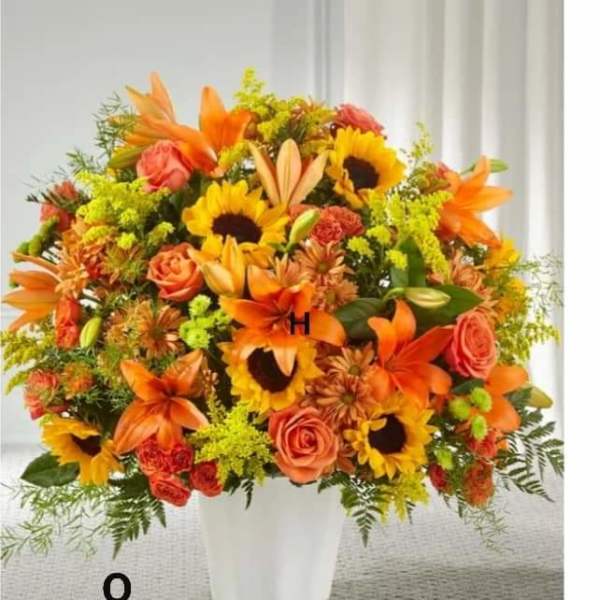 Orange and yellow mixed flower arrangement in a white vase