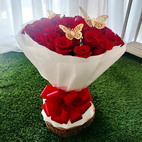 Bouquet of red roses wrapped in white paper with a red bow