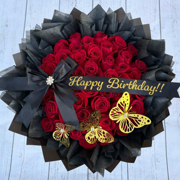 Red rose bouquet with black wrapping, a birthday ribbon, and butterfly decorations