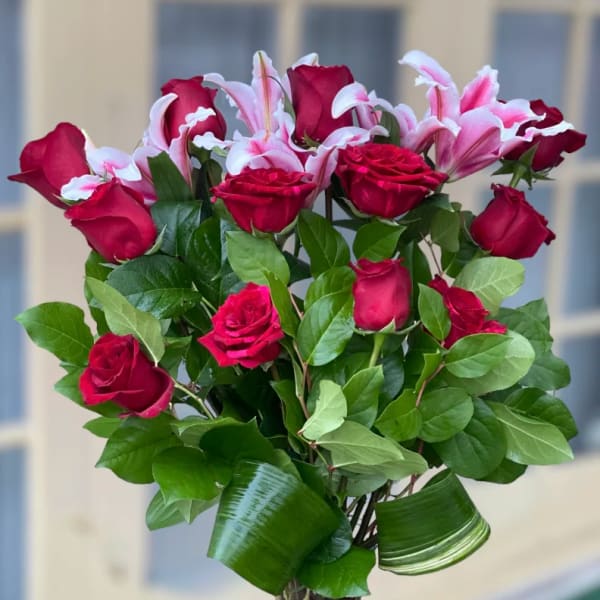 Bouquet of red roses and pink lilies in a clear glass vase