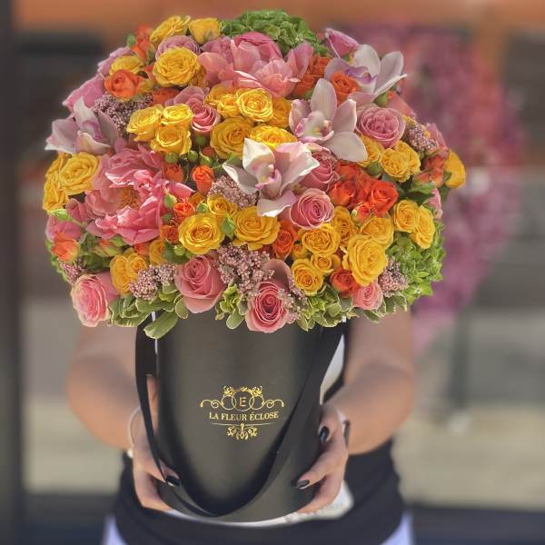 Large bouquet of pink and yellow roses in a black hatbox