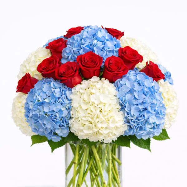Red roses and blue-white hydrangeas in a clear glass vase