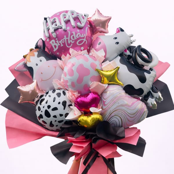 Birthday balloon bouquet with cow-print and pink foil balloons