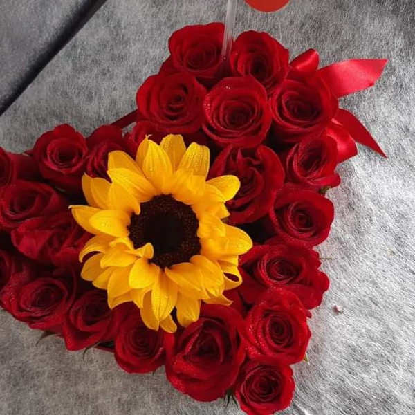 Heart-shaped bouquet of red roses with a yellow sunflower center